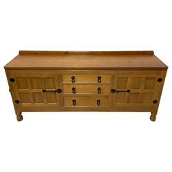 Mouseman - oak 6' sideboard, raised back over adzed top, fitted with three central drawers and flanking cupboards, enclosed by panelled doors, with wrought iron handles, latches and hinges, two fixed internal shelves, on octagonal feet, by the workshop of Robert Thompson, Kilburn 