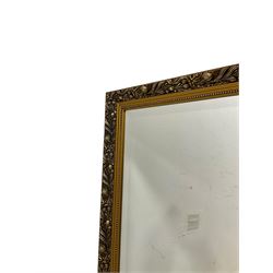 Large rectangular gilt framed wall mirror, decorated with trailing leafy branches and flowerheads, bevelled glass plate 