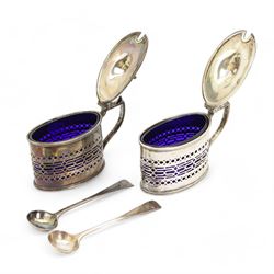 Pair of Edwardian silver mustards, oval form with pierced sides, domed cover with an urn finial by	Haseler Brothers (Edward John Haseler & Noble Haseler), Chester 1906, with a pair of Victorian silver mustard spoons by Chawner & Co, London 1856