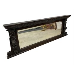 Victorian heavily carved oak wall mirror, projecting gadroon carved ovolo cornice, bevelled mirror plate within a lunette carved frame, decorated with applied fruit and foliage carved mounts, scroll carved brackets 