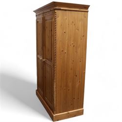 Pine double wardrobe, projecting cornice over two panelled doors, fitted with hanging rail, on plinth base