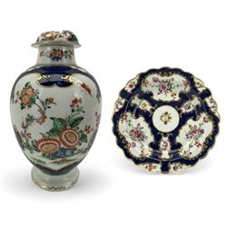 18th century Worcester tea caddy, of oval form and painted in the Kakiemon palette with reserves of flowers against a blue scale ground, H14cm together with a similar Worcester circular dish, painted with floral sprays, within a scalloped edge, blue crescent mark beneath, D19cm (2)