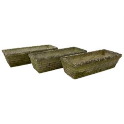 Three cast stone rusticated garden planters of tapering rectangular form 