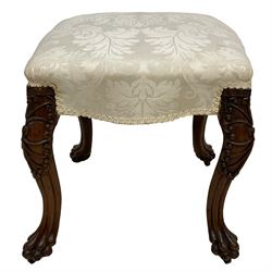 Georgian Irish mahogany dressing stool, overstuffed seat upholstered in in ivory damask fabric, the cabriole supports decorated with moulded interlacing scroll motifs with mycelium cap detail, over lobe carvings terminating to large paw feet