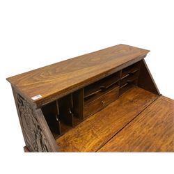Mid-to late 20th century Singapore camphor wood bureau on stand, the fall front carved with royal procession scene within a cityscape, flower head carved border, the interior fitted with drawer and correspondence shelves, two drawers below, on turned supports united by H-shaped stretchers