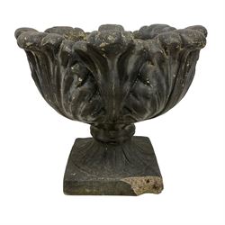 Composite stone floral shaped urn, decorated with relief overlapping anthemion leaves, on square base, in black painted finish