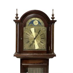 20th century - Westminster chime 8-day grandmother clock in a mahogany case, with a break arch top and brass finials, fully glazed trunk door with visible brass cased weights and pendulum, brass dial with etched dial centre and spandrels, chapter ring with Roman numerals and working moon disc to the arch, two train chain driven movement with 12 gong rods and chime selection for the quarters and hours.