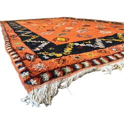 Moroccan amber ground thick pile rug, the field decorated with stylised geometric lozenges and roods, interspersed with camel motifs, the guard bands with stylised foliate and plant motifs