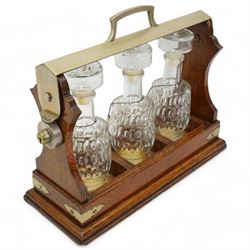 Early 20th century oak and silver plated tantalus, with matching moulded glass decanters and ceramic labels, L39cm