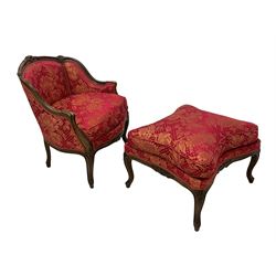 Late 20th century French design stained beech framed armchair and matching stool - the armchair with shaped and moulded frame carved with flower heads and foliage, upholstered in silk red and gold ground fabric with floral pattern, on scroll carved cabriole feet decorated with flower head carvings (W73cm, H82cm, D75cm); the footstool of concaved rectangular form with moulded frame carved with flower heads, upholstered loose cushion, on cabriole feet (70cm x 64cm, H48cm)