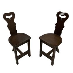 Pair of oak hall chairs, shaped back with pierced handle, on incised front supports united by arcade carved front rail and pegged stretcher 
