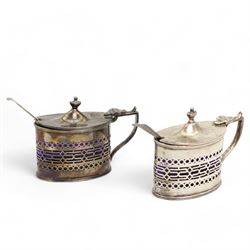 Pair of Edwardian silver mustards, oval form with pierced sides, domed cover with an urn finial by	Haseler Brothers (Edward John Haseler & Noble Haseler), Chester 1906, with a pair of Victorian silver mustard spoons by Chawner & Co, London 1856