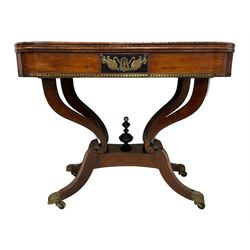 Regency inlaid rosewood card table, rectangular swivel and fold-over top with rounded corners and baize lined interior, the frieze decorated with a central ebony panel with applied gilt metal swan motifs, over a brass inlay band, raised on S-scroll supports united by concave platform base, terminating to out-splayed supports with brass cups and castors