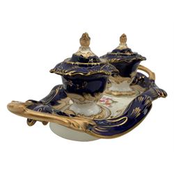 19th century porcelain inkstand, the oblong twin handled base centrally painted with a floral bouquet, flanked by two footed inkwells and covers, with rococo-inspired acanthus moulded borders and handles, pattern no. 2/3339, L26.5cm 