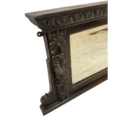 Victorian heavily carved oak wall mirror, projecting gadroon carved ovolo cornice, bevelled mirror plate within a lunette carved frame, decorated with applied fruit and foliage carved mounts, scroll carved brackets 