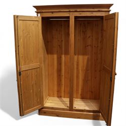 Pine double wardrobe, projecting cornice over two panelled doors, fitted with hanging rail, on plinth base