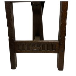 Pair of oak hall chairs, shaped back with pierced handle, on incised front supports united by arcade carved front rail and pegged stretcher 