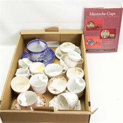 Victorian and later porcelain moustache cups, some with saucers, and related book, in one box