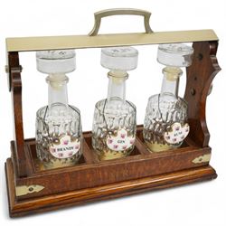 Early 20th century oak and silver plated tantalus, with matching moulded glass decanters and ceramic labels, L39cm