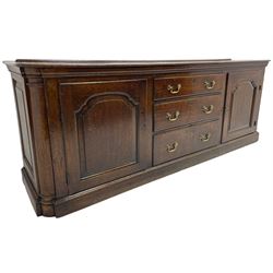 George III oak dresser base, rectangular top with rounded corners over moulded frieze rail, canted corners with turned quarter columns, fitted with three drawers with moulded edges flanked by two cupboards, enclosed by ogee arched fielded panelled doors, panelled sides, moulded plinth base