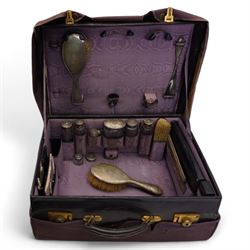 Ladies leather travelling dressing case, the watered silk interior with silver mounted glass bottles, silver backed brushes, folding leather writing case, sewing case, ink well etc, the silver hallmarked for Sheffield 1918, Maker Walker & Hall 50cm x 36cm in outer canvas case