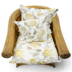 Pair of rattan cane work conservatory armchairs, with loose cushions upholstered in floral fabric