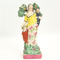 Three early 19th century Staffordshire Pearlware figures depicting Faith, Hope and Charity, Faith standing next to a shield bearing a cross, on an oval encrusted and moulded base H20cm, Charity stood holding a child and another by her side and Hope standing with an anchor, both on square bases (3)