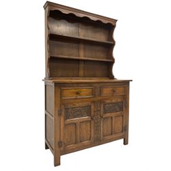Georgian design oak dresser and two-tier plate rack, fitted with two drawers over two panelled cupboard doors, each carved with floral lunettes