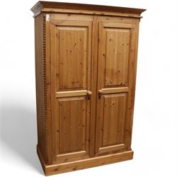 Pine double wardrobe, projecting cornice over two panelled doors, fitted with hanging rail, on plinth base