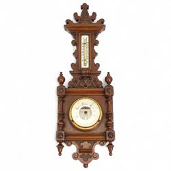 Early 20th century Edwardian aneroid barometer, in a mahogany case with scroll carving, turned finials and pendants, boxed mercury thermometer recording temperature in degrees Fahrenheit and centigrade on opaline register, open dial barometric register with gothic script predictions, steel indicating hand and brass recording hand.