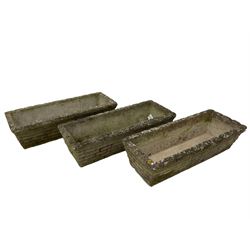 Three cast stone rusticated garden planters of tapering rectangular form 